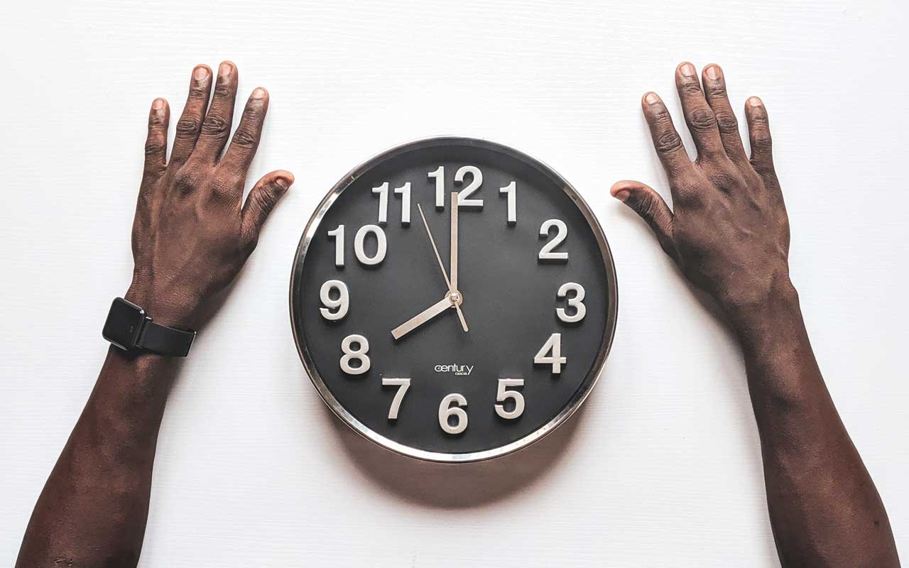 一个黑人的手在模拟时钟旁边。