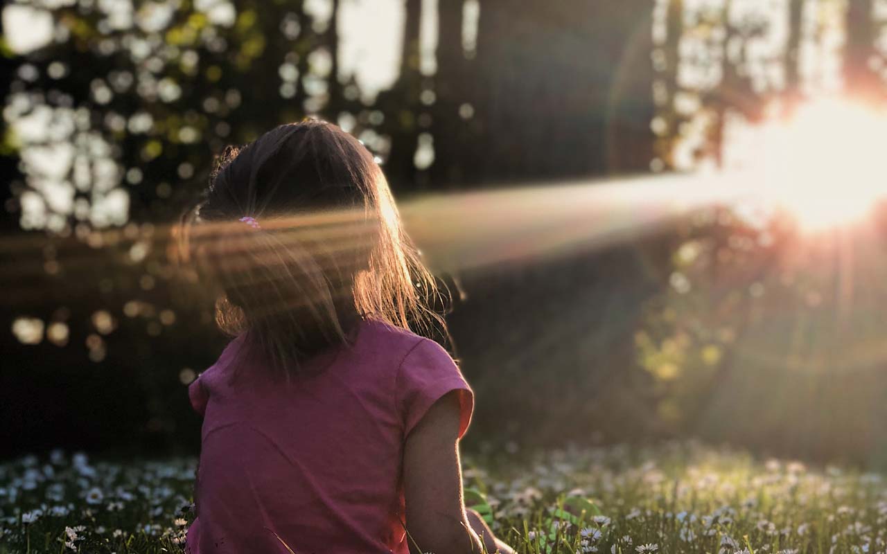 一个年轻的女孩坐在大自然的一束光里。选择一个自然的环境来冥想可以帮助你集中注意力。