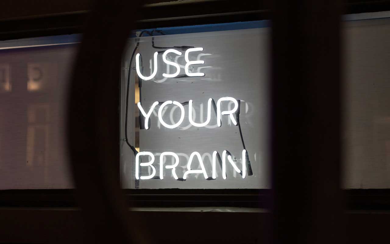 黑色背景下的白色霓虹灯标牌上写着“运用你的大脑”