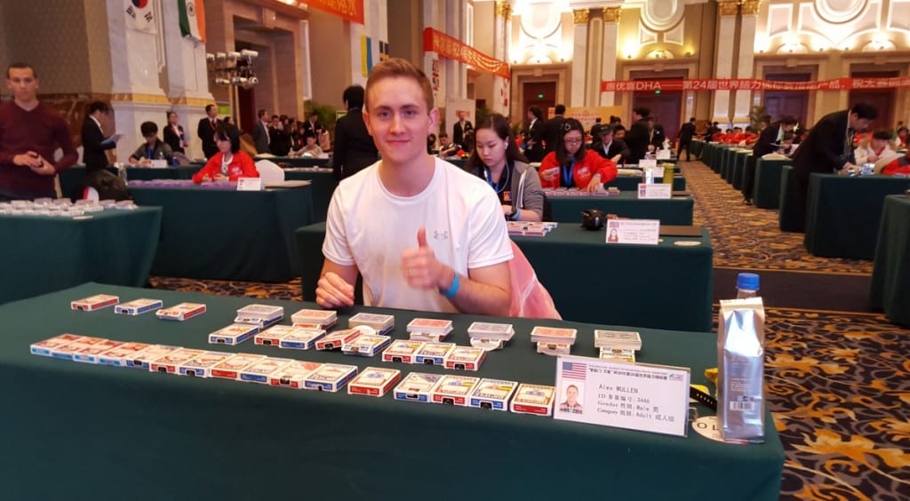 亚历克斯·马伦坐在一张桌子上，手里拿着几副扑克牌