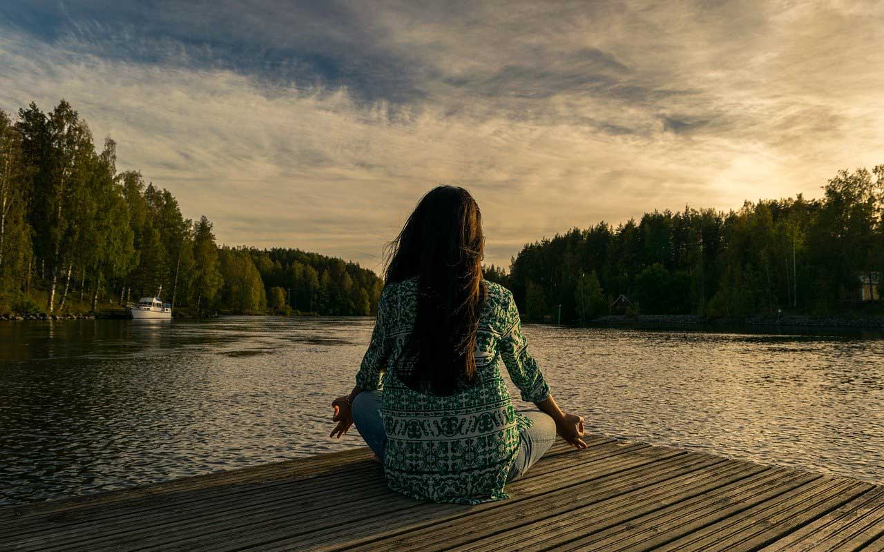 一个女人在湖边冥想，练习正念。