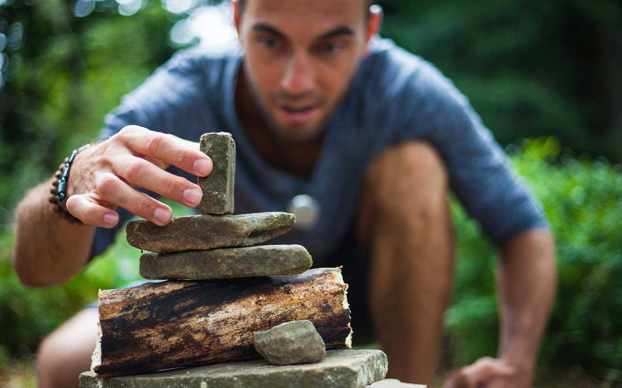一个男人专注于堆叠石头。