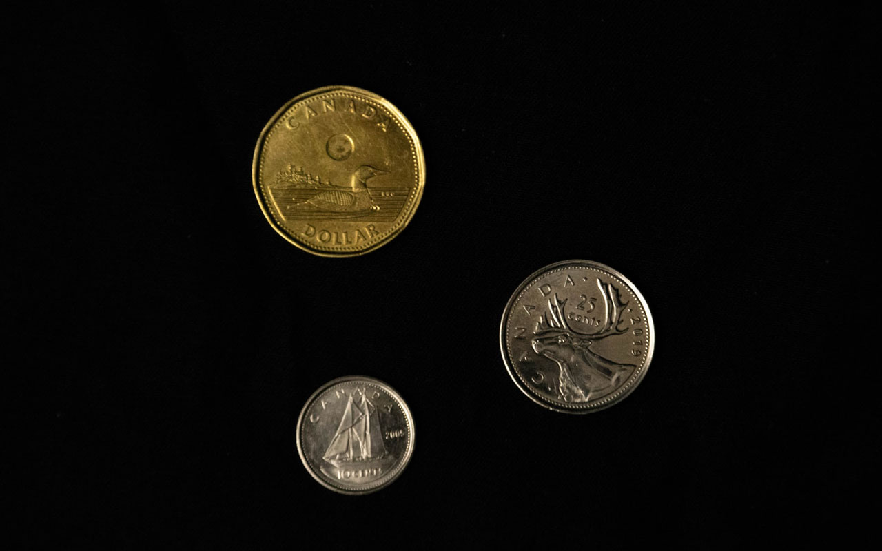 三加拿大硬币反对黑背景。