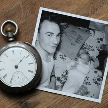 一个男人和一个婴儿的黑白照片，旁边放着一只怀表。