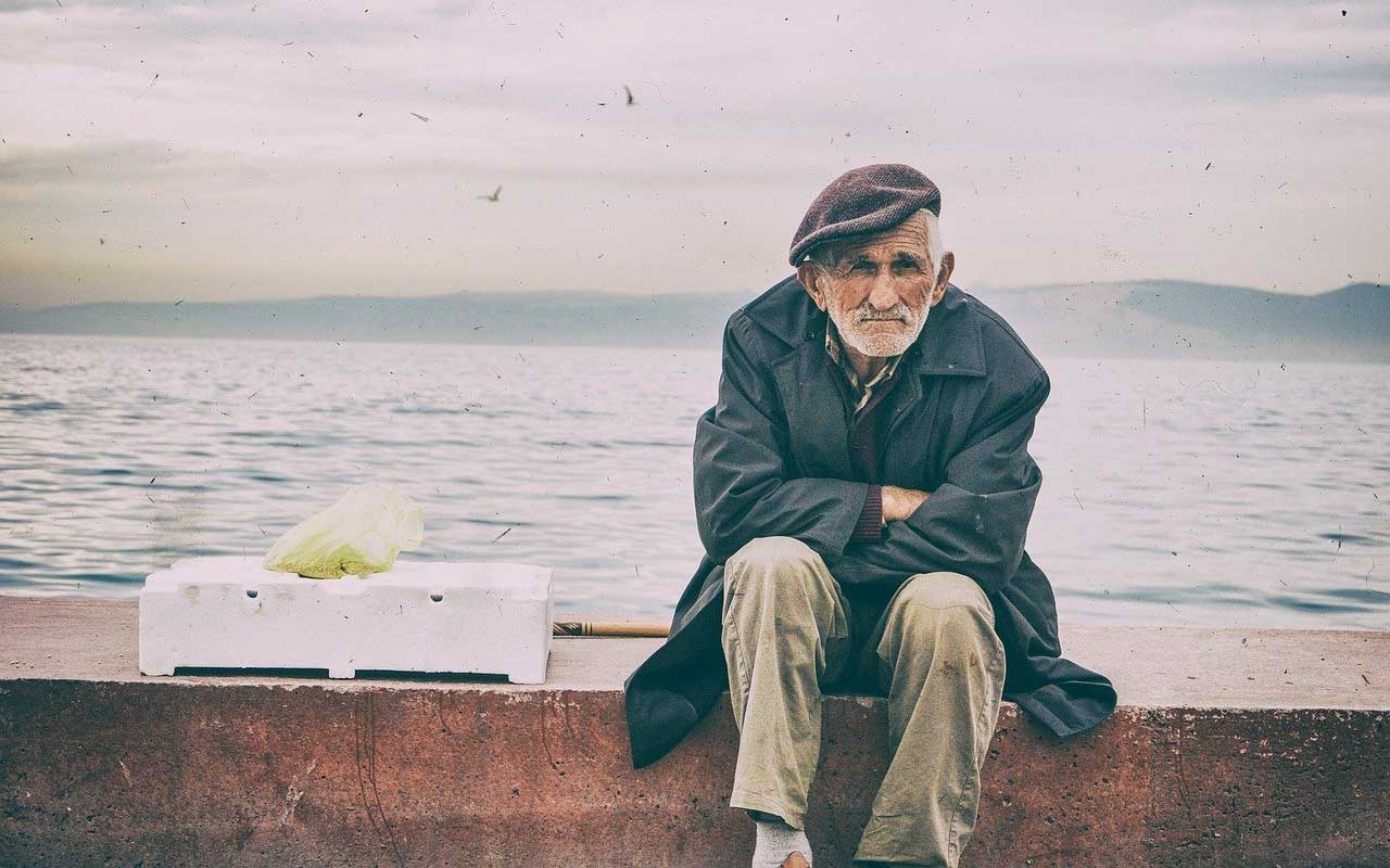 一位老人坐在海堤上。
