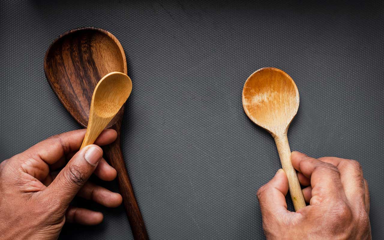 一个人在手中拿着木制的勺子，在桌子上间隔开。