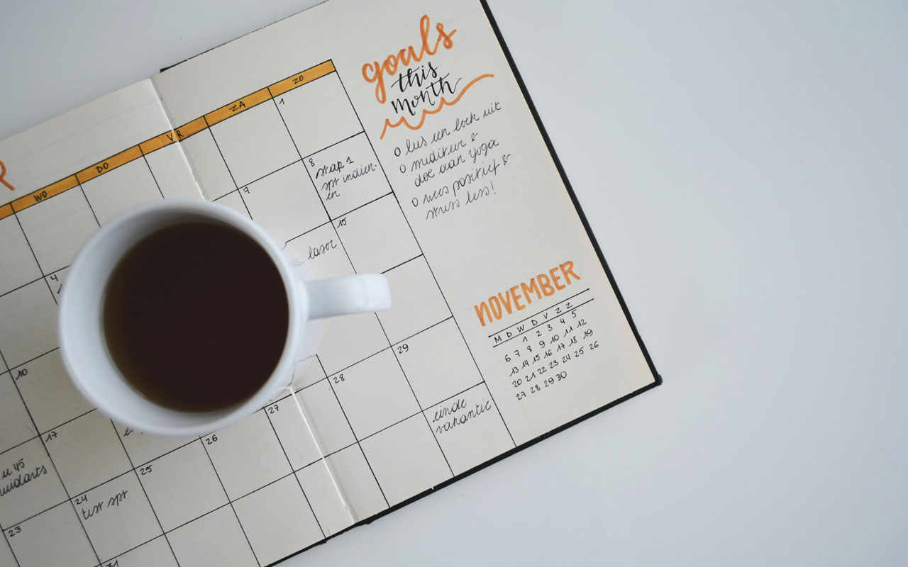 与一杯咖啡的一个目标日历坐在上面。