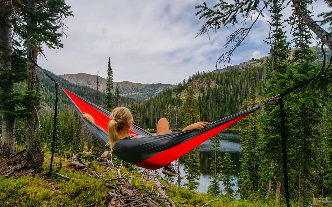 一个女人在荒野的湖边的吊床上休息。想象自己在吊床上放松是一种想象放松。