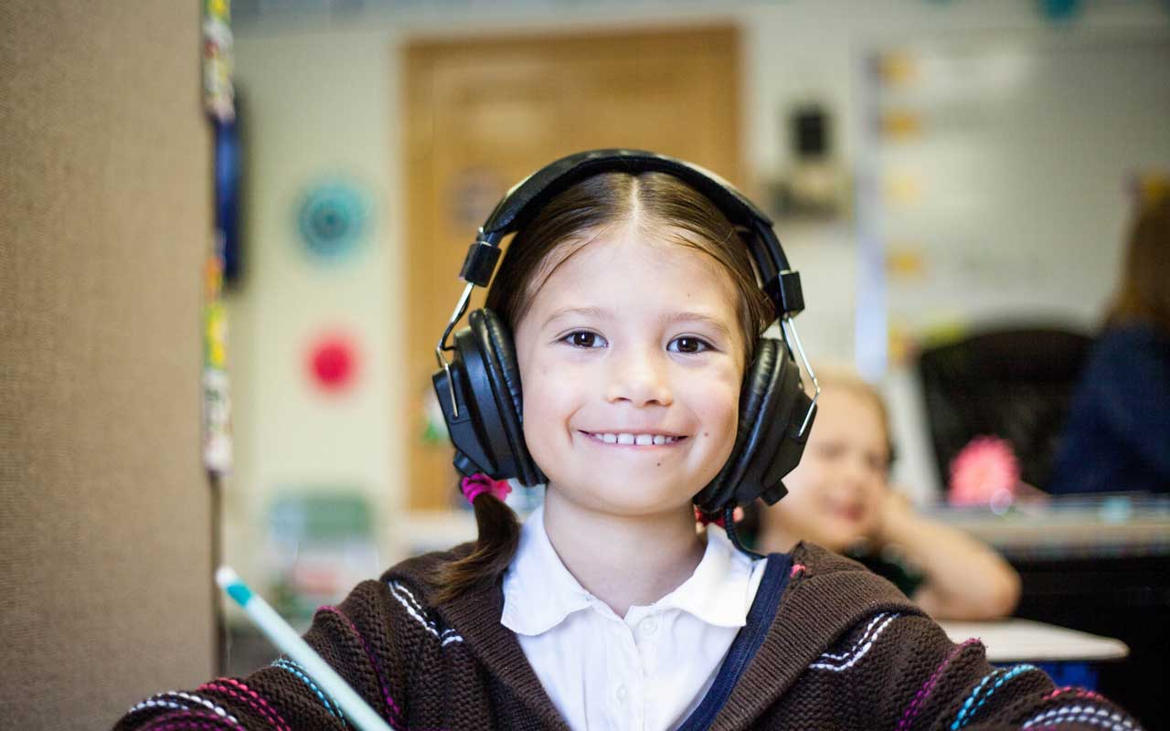 一个戴着耳机的年轻女孩对着镜头微笑。