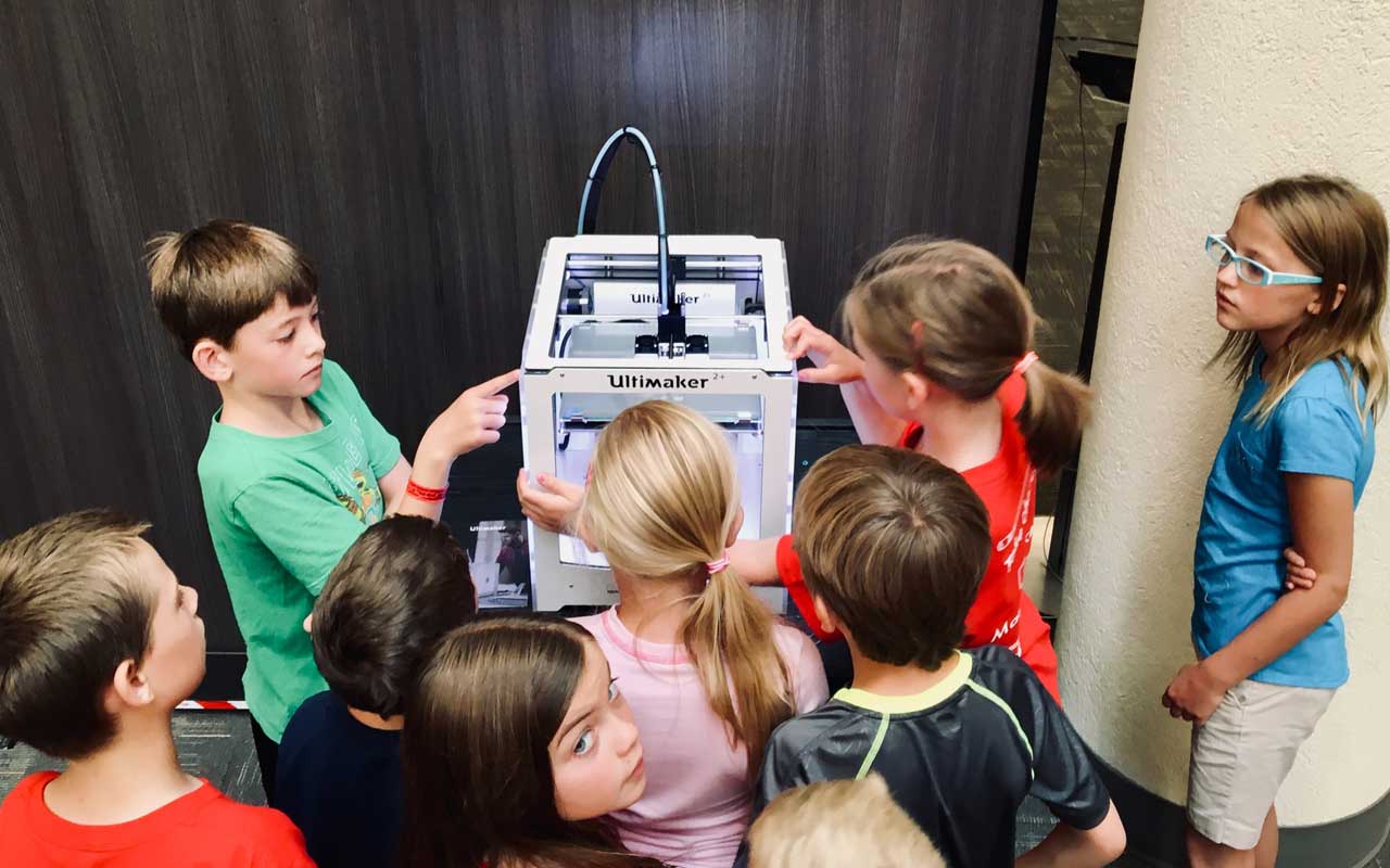 学生们聚集在3D打印机周围，这是创造性解决问题的一个例子。
