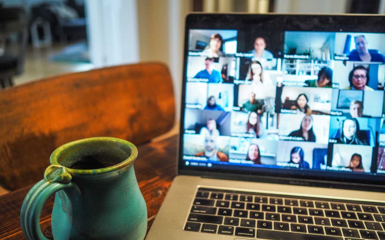 一台笔记本电脑旁边放着一杯茶，上面正在进行一场集体视频会议。由于大流行带来的健康问题，研究小组和问责伙伴可能不会亲自会面。