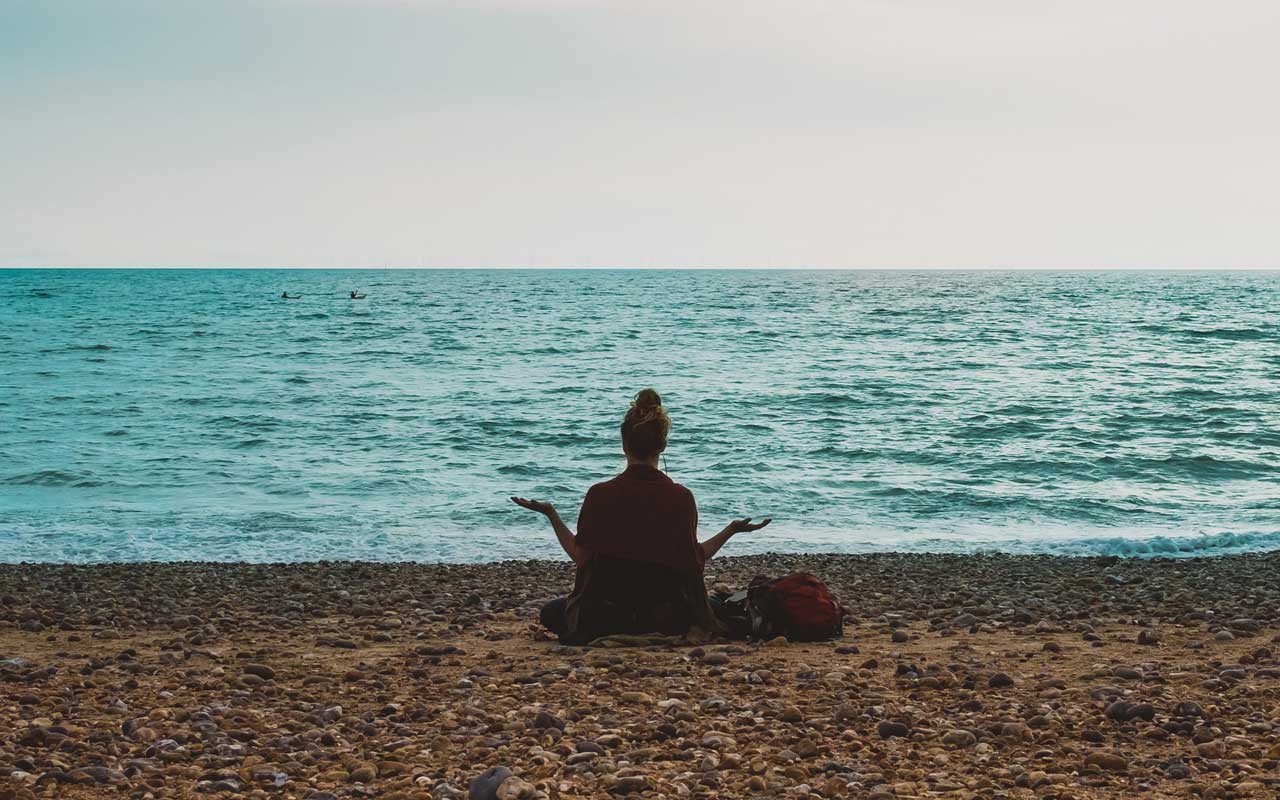 一个女人在海边冥想。冥想可以帮助你集中精力学习，提前清理思绪。
