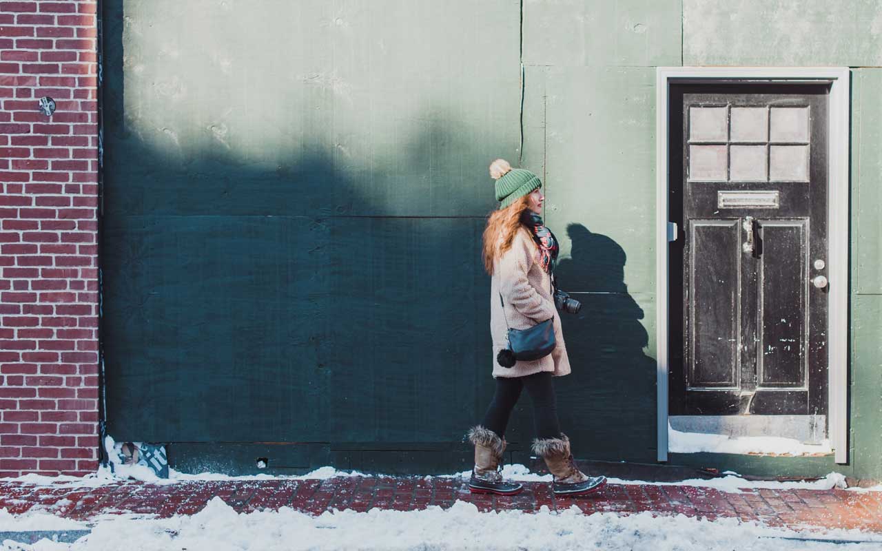 一个女人走在下雪的城市街道上。没有科技的散步是一种很好的集中注意力的方式。