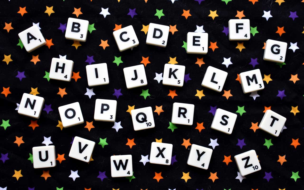 从一个拼写游戏的字母表瓦片布局反对满天星斗的背景。