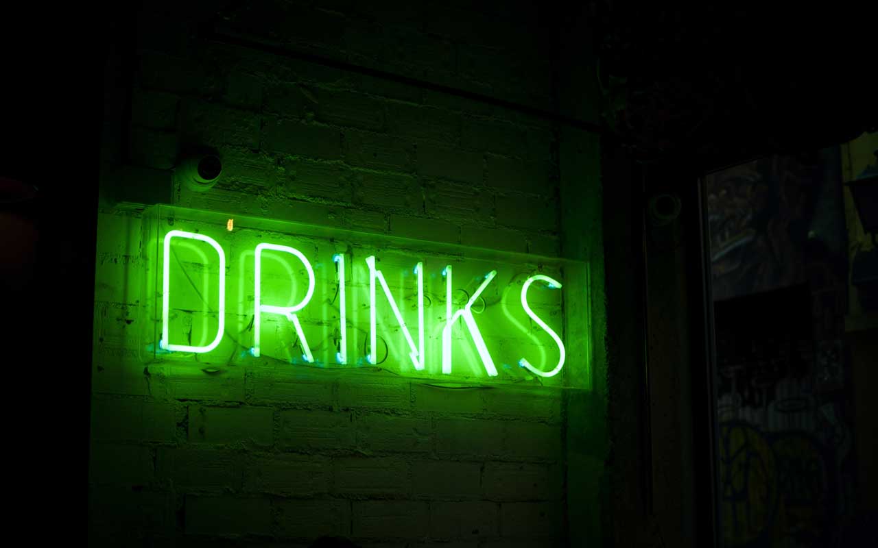 绿色的霓虹灯标志说饮料。酒精消费可以损害成年人的记忆。
