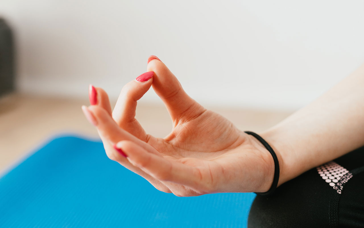有红色指甲盖的一个妇女的手，在瑜伽mudra。冥想的思想和集中度提供了认知益处。