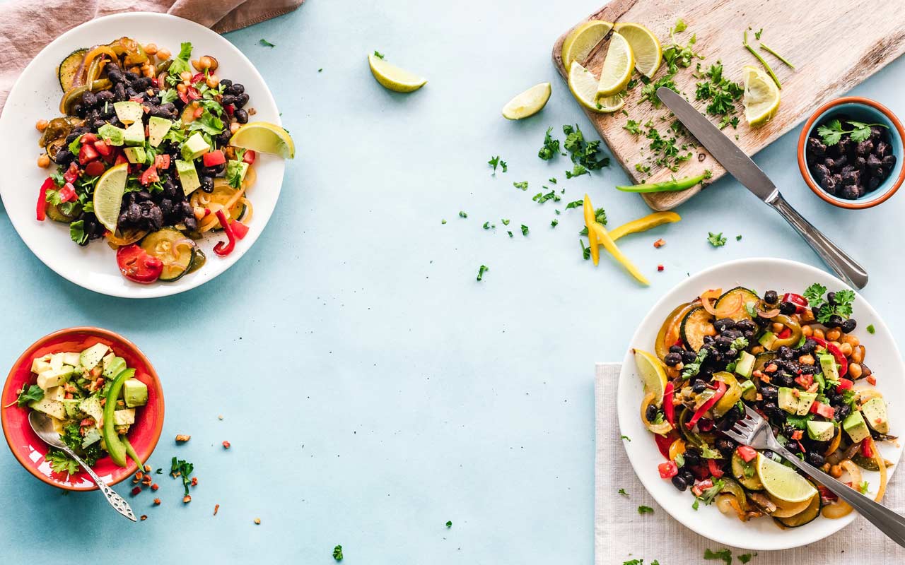 蓝色的桌布上放着沙拉碗和盛满酸橙的切菜板。像水果和蔬菜这样的健康食物是天然的记忆力增强剂。