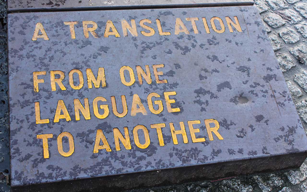 一块灰色的石头躺在地上，上面有黄色的文字写着:“从一种语言到另一种语言的翻译。”