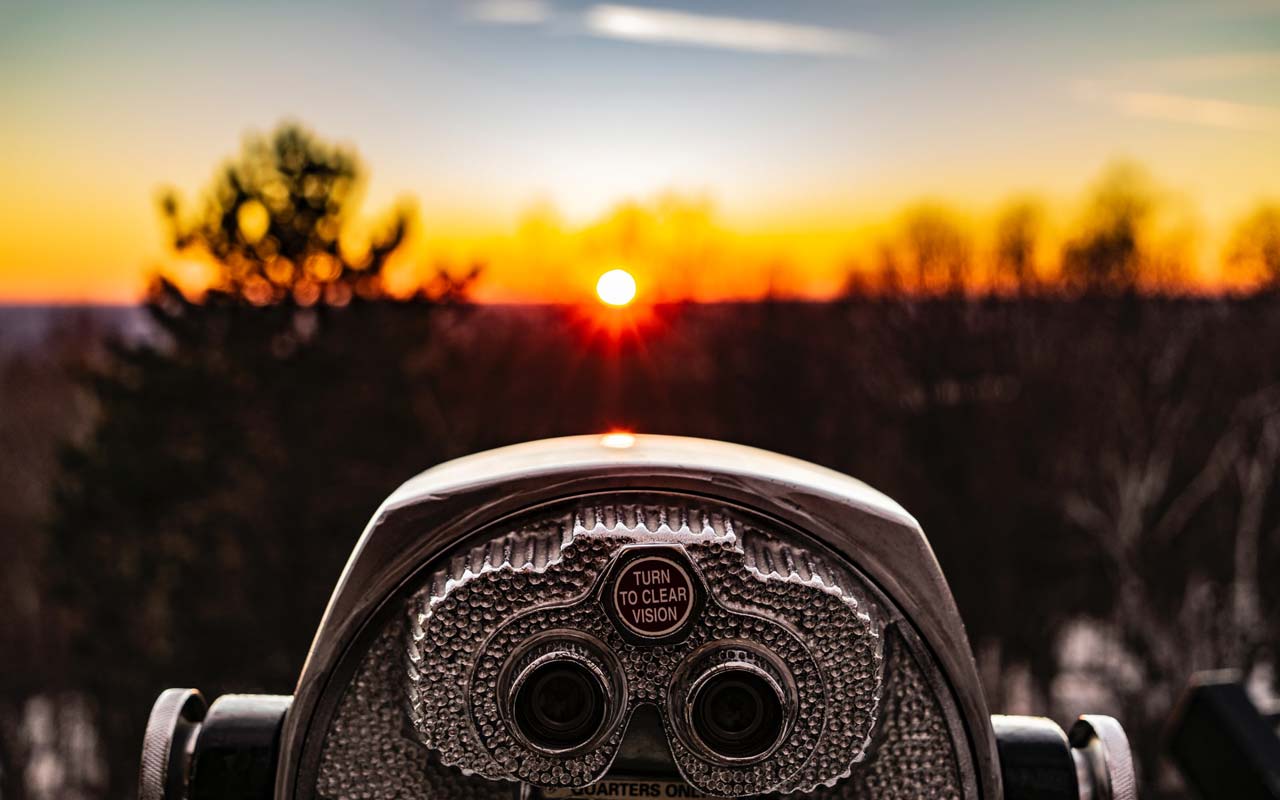 塔观看者（在立场上的双筒望远镜）俯视在日落的焦点地平线。