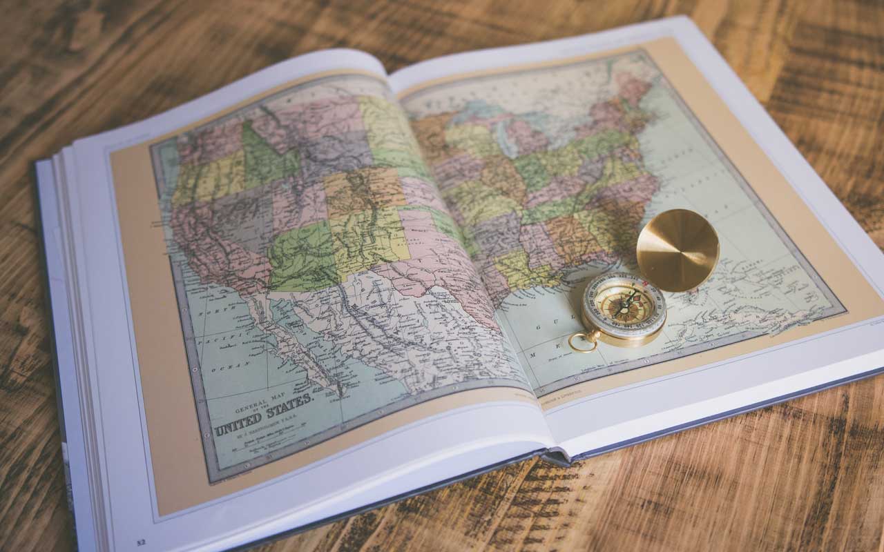 一张木桌上放着一张美国地图和一个指南针。