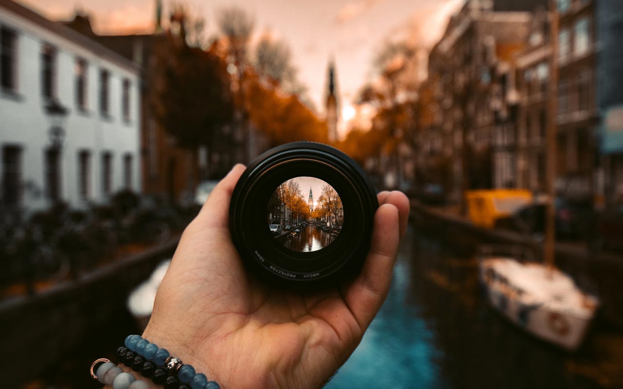 一个人拿着相机镜头。该重点在阿姆斯特丹展示了一条运河，其中其余的照片在软焦点中。