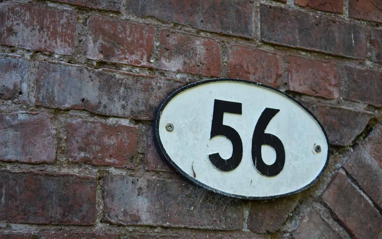 在白色的房子号码“56”与反对砖墙的黑号。56是N背面测试的该示例中的第二个数字。