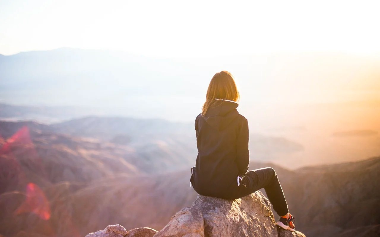 一名妇女坐在岩石与山景